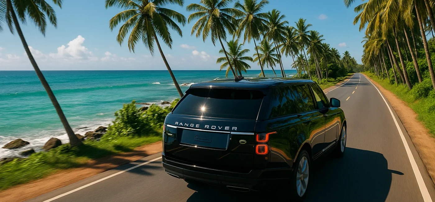 Luxury Range Rover driving along a scenic Sri Lankan coastal road with ocean views and palm trees.